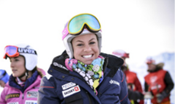 Woman wearing ski clothing, with ski goggles pulled up onto her helmet